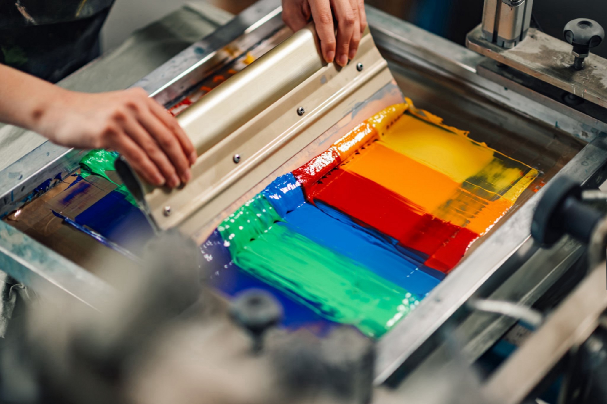 Professional screen printing machine applying vibrant rainbow ink to custom printed activewear fabric in OEM factory