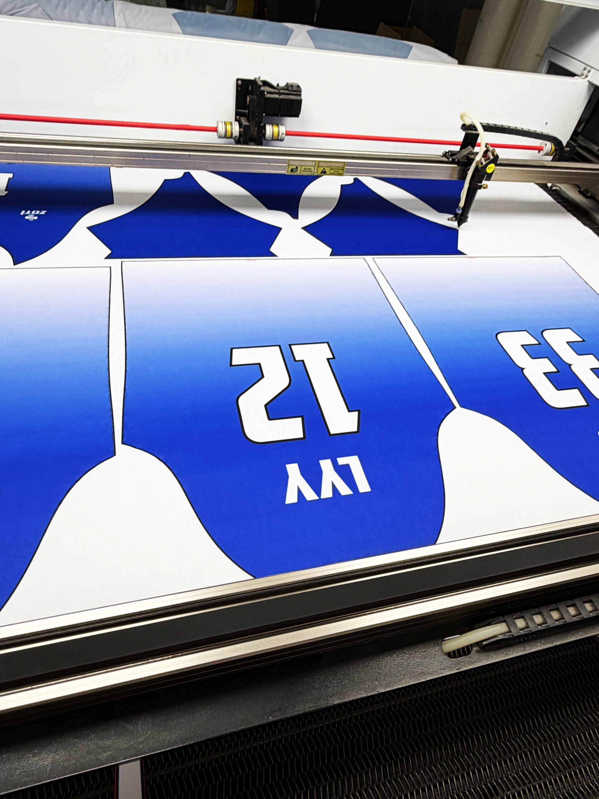 Close-up of laser beam cutting precise curved neckline on sportswear fabric panel